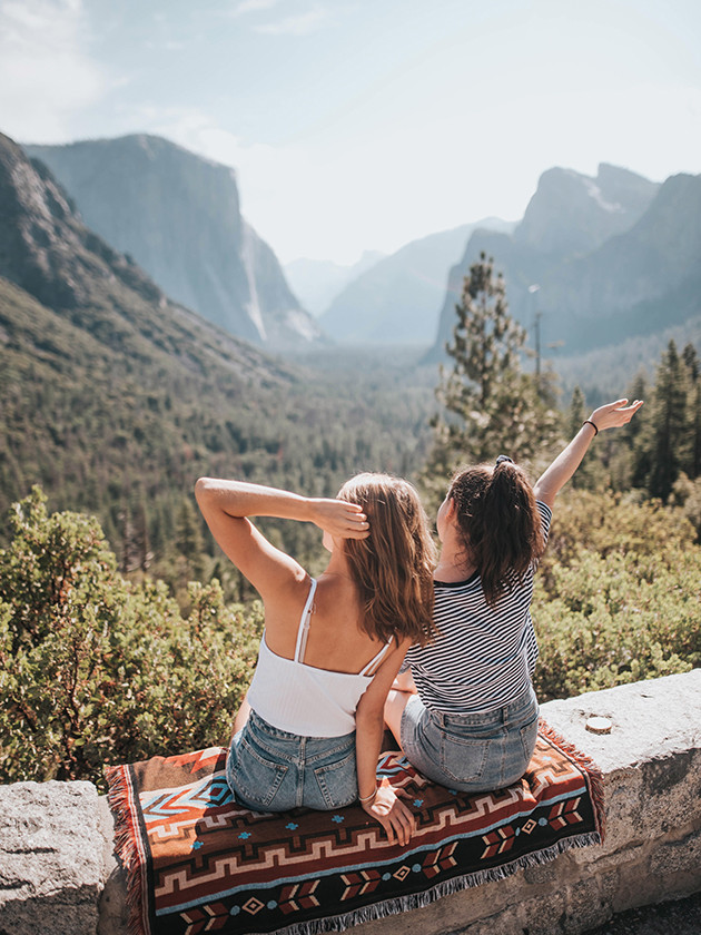 Two Topdeck travelers sitting on a ledge overlooking the beautiful Yosemite National Park.