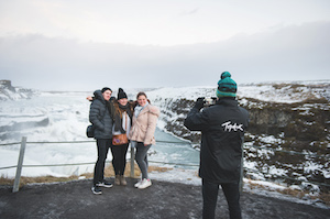 Topdeck travelers posing for a photograph in front of Iceland's natural wonders: the Gullfoss Waterfall.