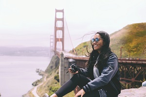 Topdeck traveler sitting on ledge with the Golden Gate Bridge in the background.