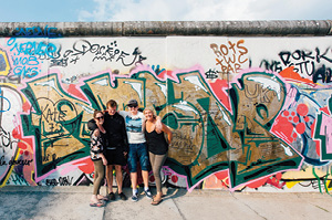 Topdeck travelers posing in front of the graffiti laden remains of the last remnants of the Berlin Wall.