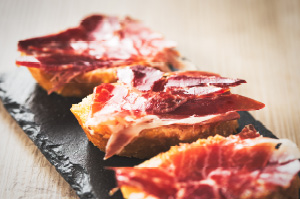 A tapas plate of bread topped with Spanish cured meats.