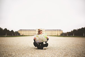 Topdeck traveler sitting looking at a map in front of the Vienna State Opera Building.