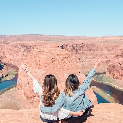 Two women posing for a photo in front of the Grand Canyon.