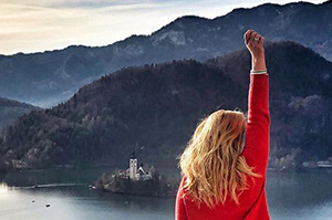 A Topdeck traveler raising their hand up looking over the famous Lake Bled in Slovenia.