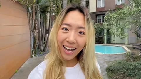 Person with blonde hair smiling with a pool behind them.