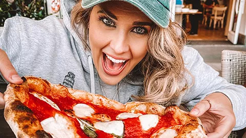 Person holding up an Italian pizza in Italy.