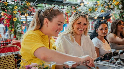 Person wearing a yellow polo uniform picking up escargot off a plate in Paris.
