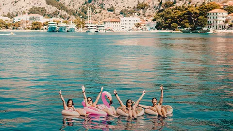 Four people floating in inflatable rings with their hands in the air.