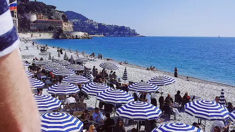 Blue and white umbrellas line the stoney beach of Nice, France.