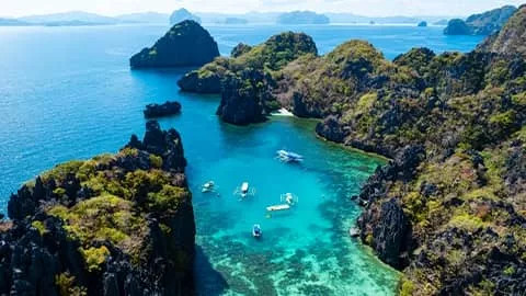 View of a Palawan bay with bright blue water and lush tree covered islands.