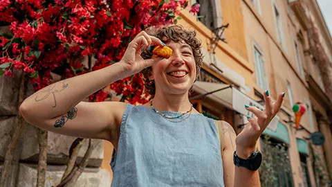 Person holding up pastry to their eye while poking out their tongue.