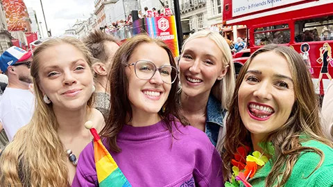 Four people smiling together at the pride parade in London.