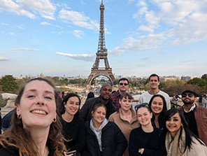 Topdeck tour group posing for a photo in front of the famous Eiffel Tower in Paris.