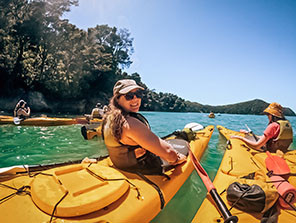 Topdeck travelers smiling at the camera during a Kayaking trip through New Zealand.