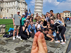 Topdeck Tour group giving a funny hand gesture while doing a group photo in front of the Leaning Tower of Pisa.