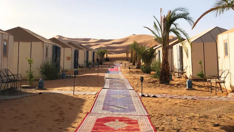 Mats laid out in a line with tents on each side set up in the desert.