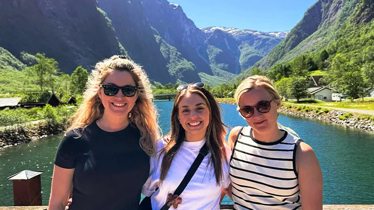 People standing together smiling in front of a water in a valley.