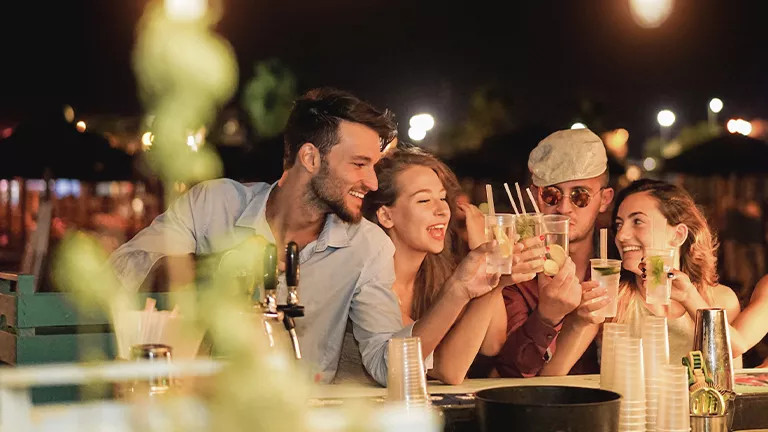 Group of people holding their drinks together in a social gesture.