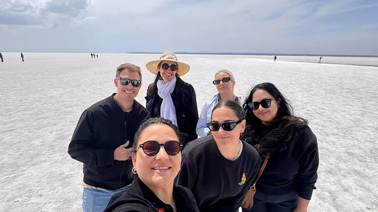 Small group of people posing together on a salt flat.