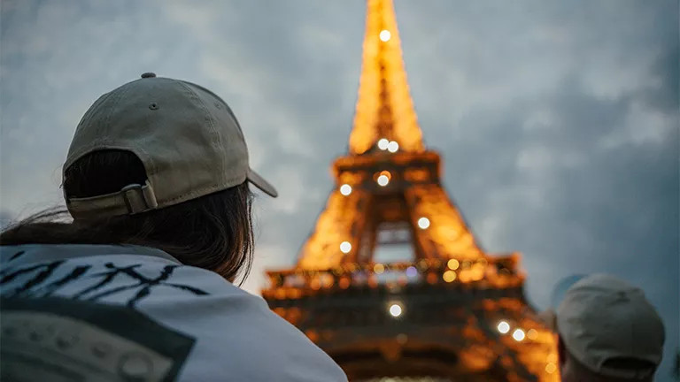 The Eiffel Tower sparkling at night over a person’s shoulder.