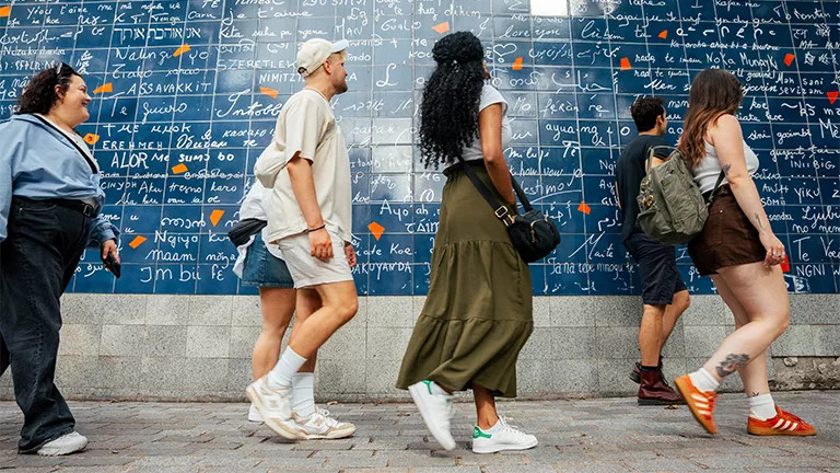 People walking past the Wall of Love, located in Montmartre, Paris.