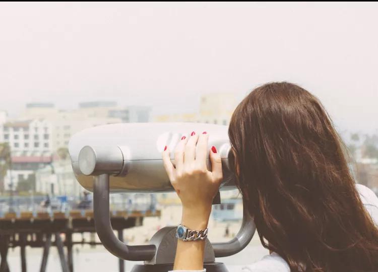 Topdeck traveler looking through binoculars at Fisherman's Wharf Pier in Los Angeles.