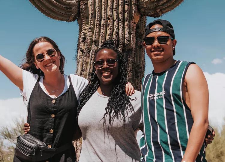 Topdeck travelers standing in front of a cactus on their trip through Nevada.