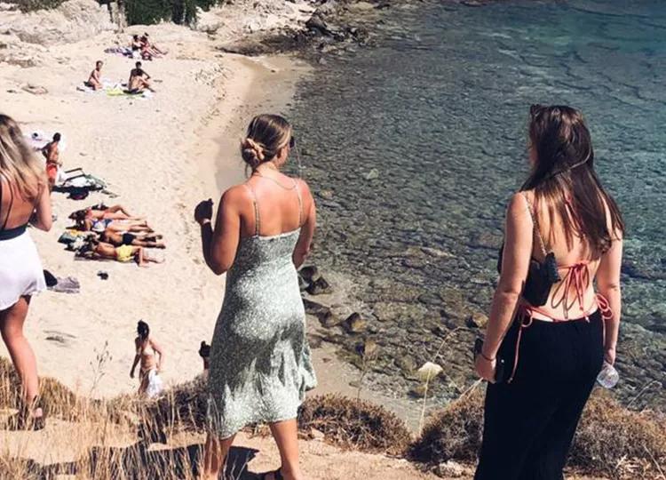 Topdeck travelers walking down a path to a beach in Greece.