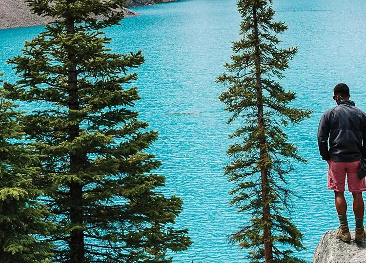 A Topdeck traveler, looking out over the clear blue waters of Canada's Morraine Lake.