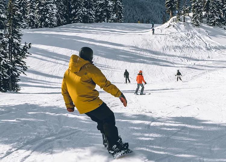 A picture of a Topdeck tour group, snowboarding and skiing down the mountains of Whistler.