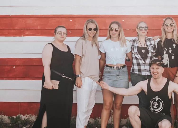 People from a Topdeck tour across the USA posing in front of the Stars and Stripes for a photo.