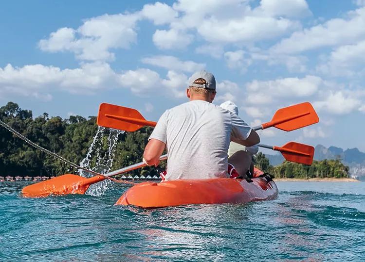 Topdeck travel group kayaking in a line across Cheow Lan lake in Thailand.