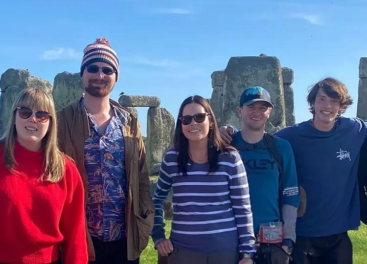 Topdeck travellers taking a group photo in front of the iconic Stonehenge landmark.