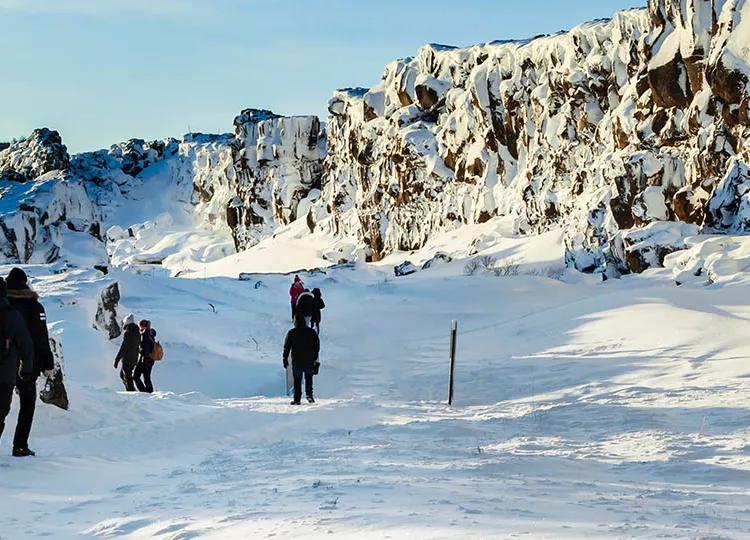 Topdeck tour group trekking across the snowy fields of Thingvellir National Park in Iceland.