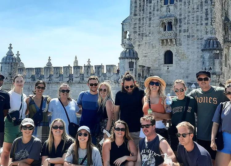 Topdeck tour group posing for a photo in front of Lisbon’s famous Torre De Belem Tower.