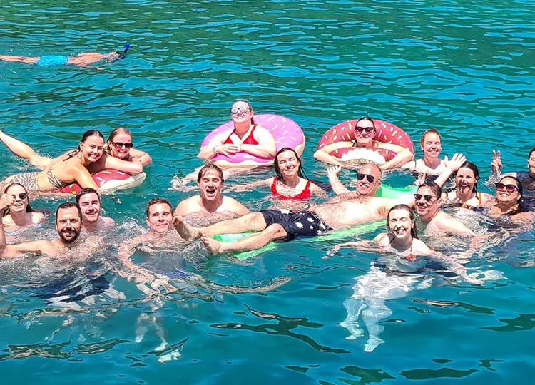 Topdeck tour group posing for a photo while swimming in the crystal blue waters of Turkey.