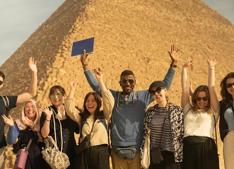 A group of Topdeck travellers pose for a photo in front of one the iconic Pyramids of Egypt.