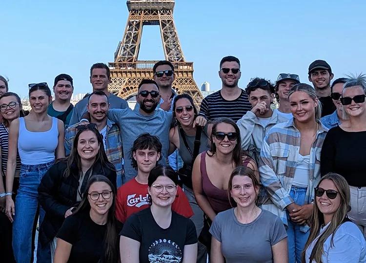 Topdeck tour group taking a photo together in front of the famous Eiffel Tower of Paris during their Get Social: Mega European trip