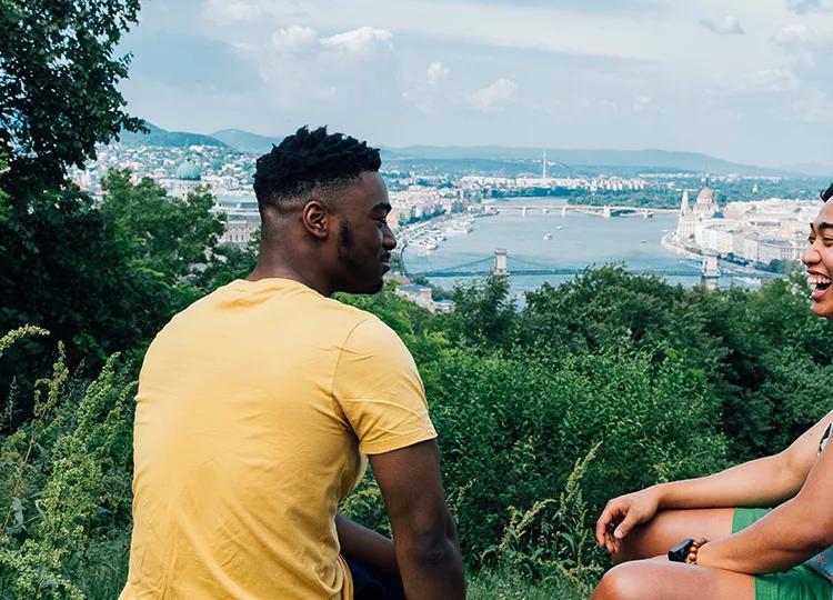 Two Topdeckers chatting away on a hill looking over the city of Budapest.