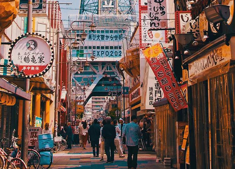 Advertisements for izakayas and bars adorn the busy Osaka street.