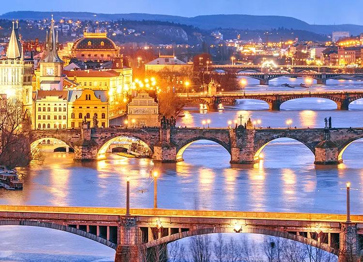 A view of the bridges leading out of Prague, lit up at night.