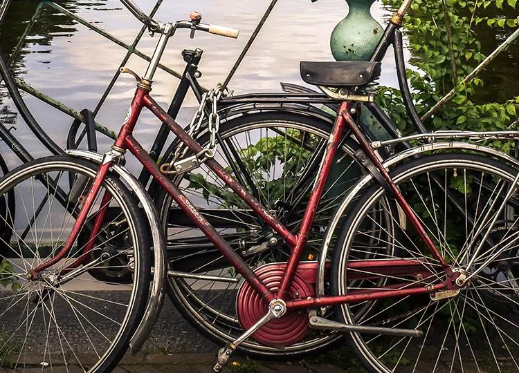 A lone bike leaning on the railing of a road looking out over one of the canals in Amsterdam.