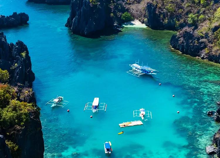 An aerial view of 4 Boats and two platforms are moored off the crystal blue waters of Palawan Island in the Phillipines.