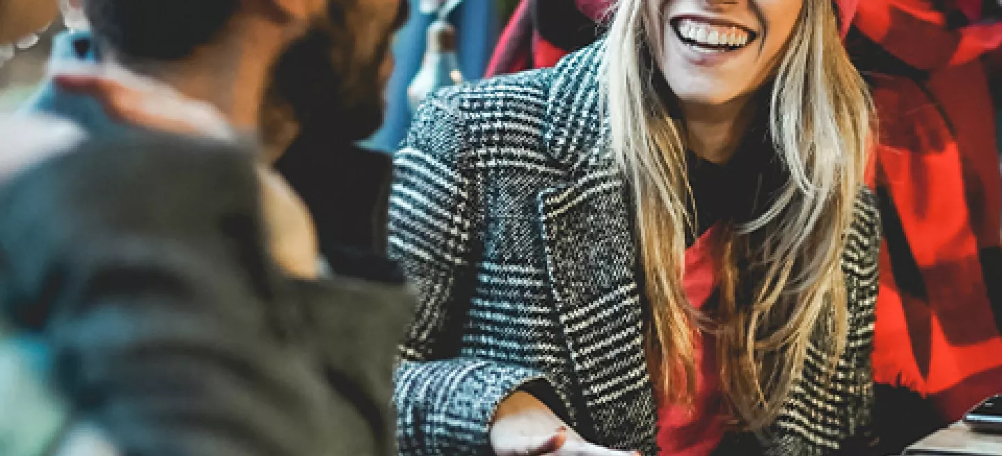 Small group of people wearing winter clothing talking at an outdoor restaurant table in Iceland.