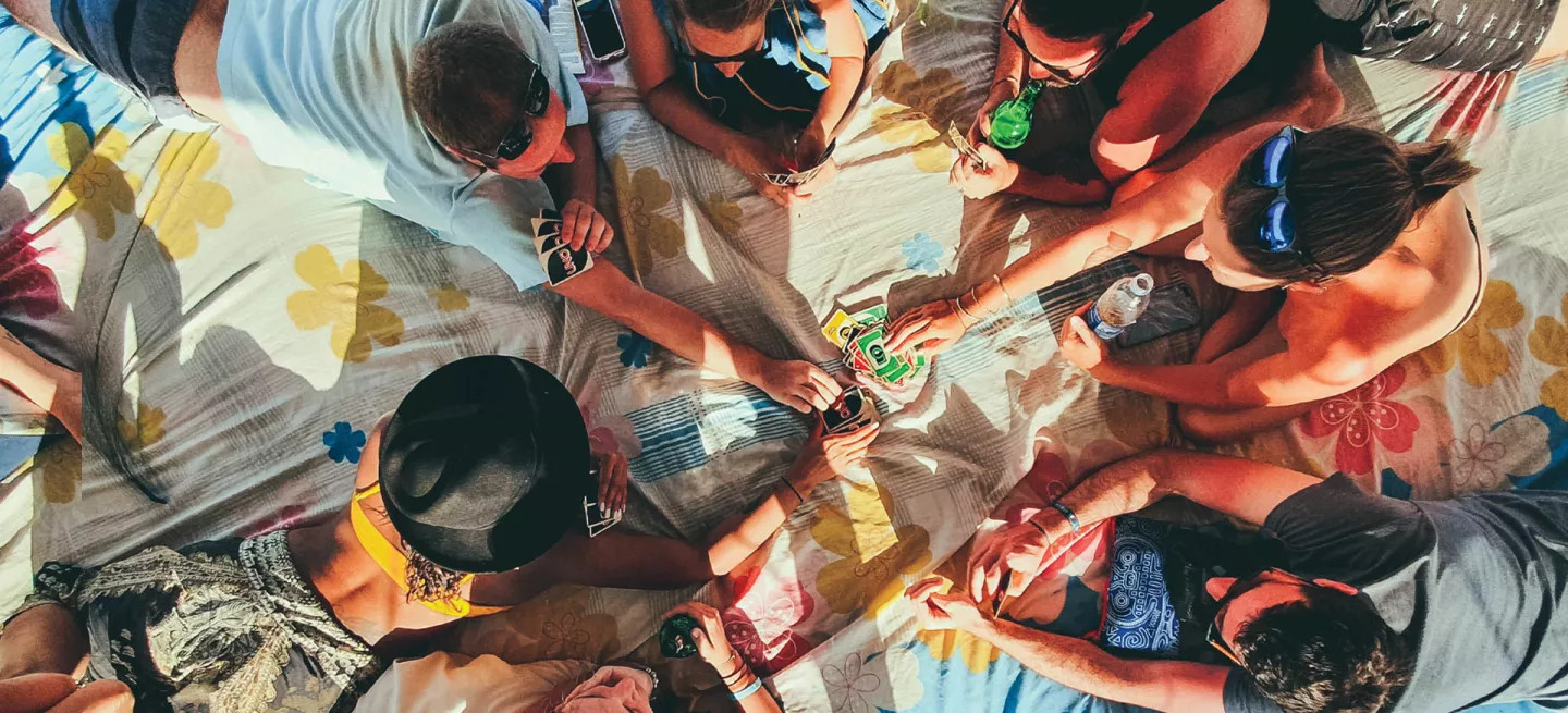 Birds eye view of people laying down on a blanket playing a colourful card game.