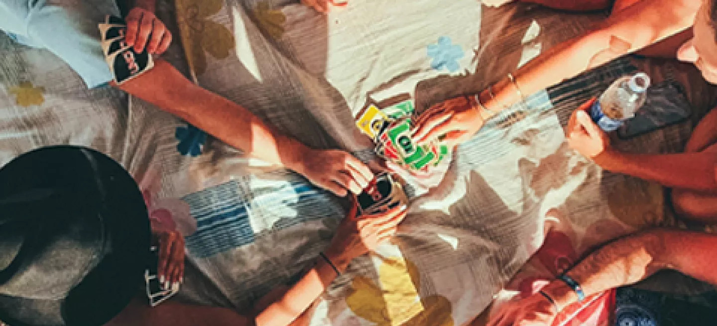 Birds eye view of people laying down on a blanket playing a colourful card game.