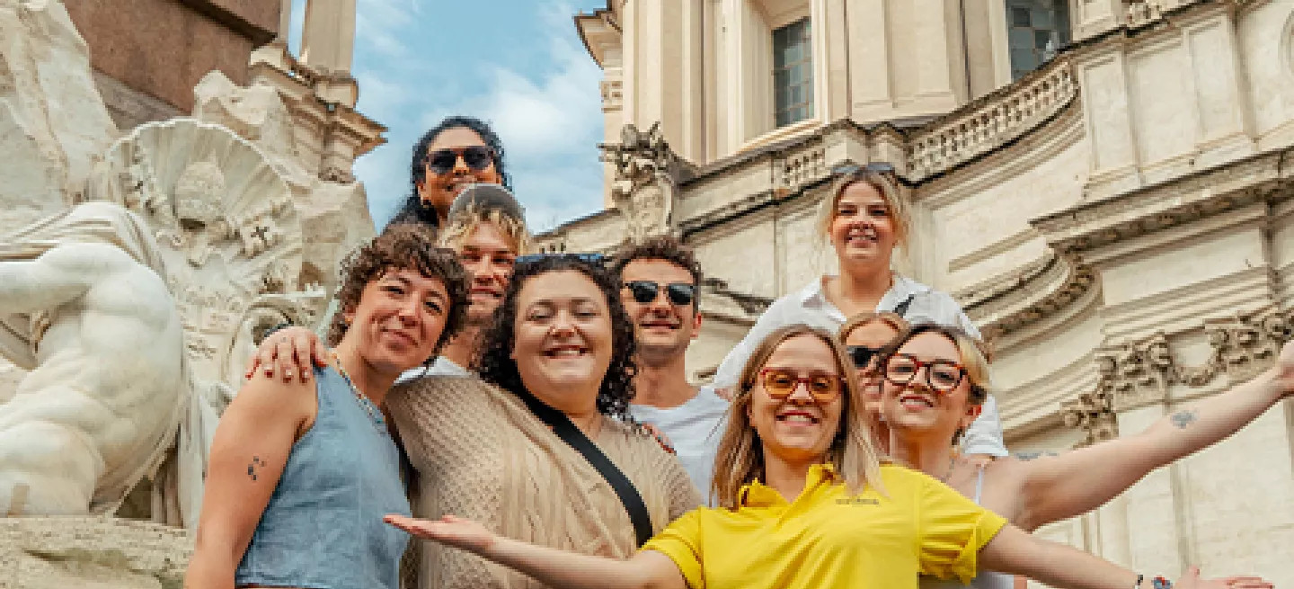 People posing in a group in front of a fountain in Rome.