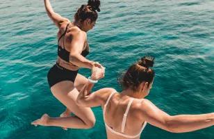 Two Topdeck travelers jumping into the clear waters of the Adriatic sea on a sailing trip in Croatia.