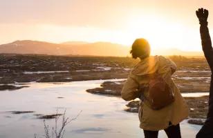 Two Topdeck travelers trekking through Iceland's countryside as the sun sets.