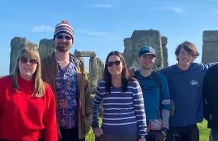 Topdeck travellers taking a group photo in front of the iconic Stonehenge landmark.